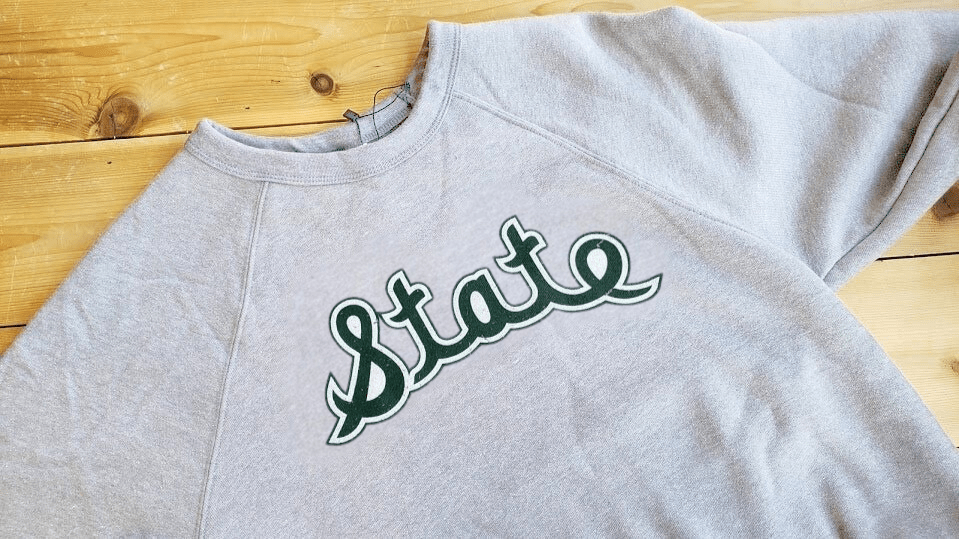 Michigan State Spartans MSU Crewneck Sweatshirt Vintage Logo Magic Johnson Era Nudge Printing on wood table laying flat