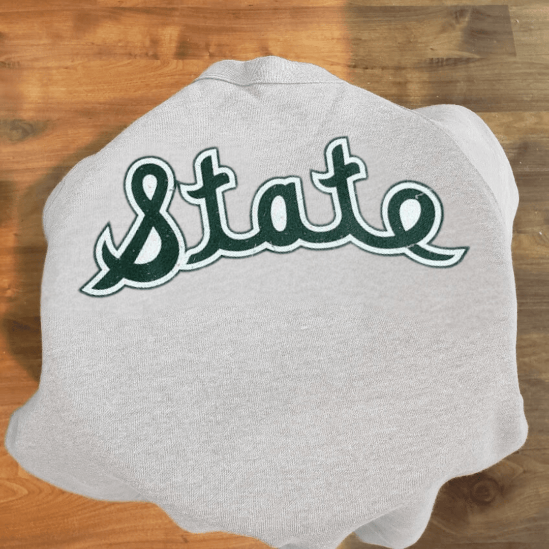 Michigan State Spartans MSU Crewneck Sweatshirt Vintage Logo Magic Johnson Nudge Printing on Stool with wood floor in background