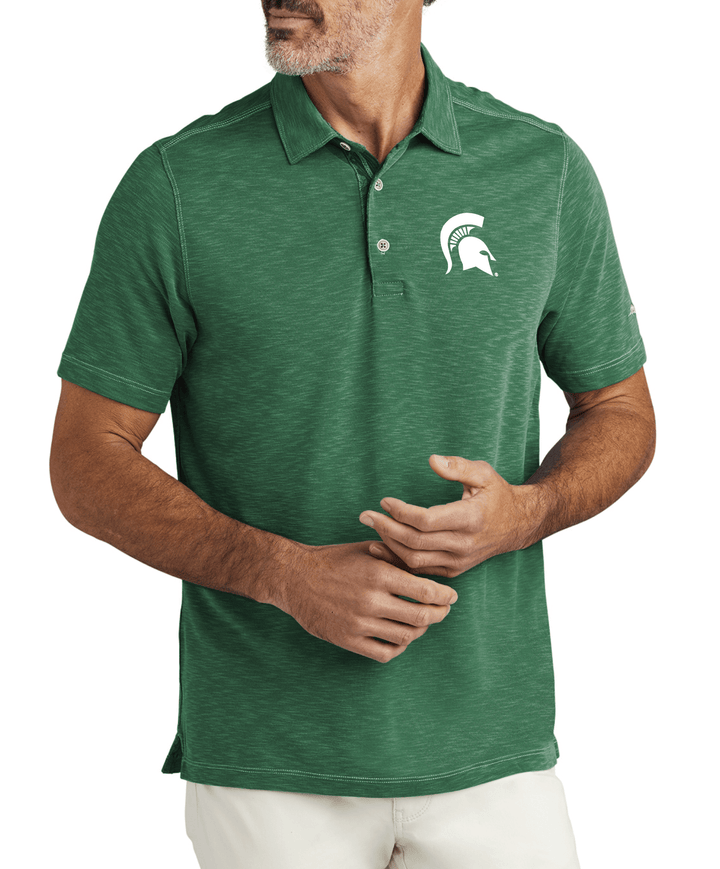 Michigan State Tommy Bahama Branded Polo embroidered on left chest with white Spartan Helmet logo from Nudge Printing on Male Model with hands in front