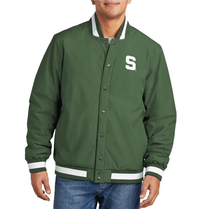 Male model wearing a green Michigan State varsity jacket with a Block S logo embroidered in white thread on the left chest