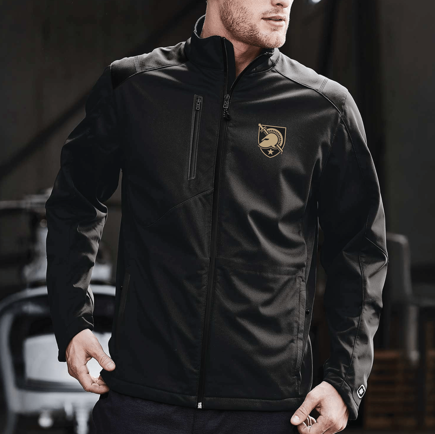 Male model wearing a black West Point jacket from OGIO featuring the Black Knights shield embroidered on the left chest.