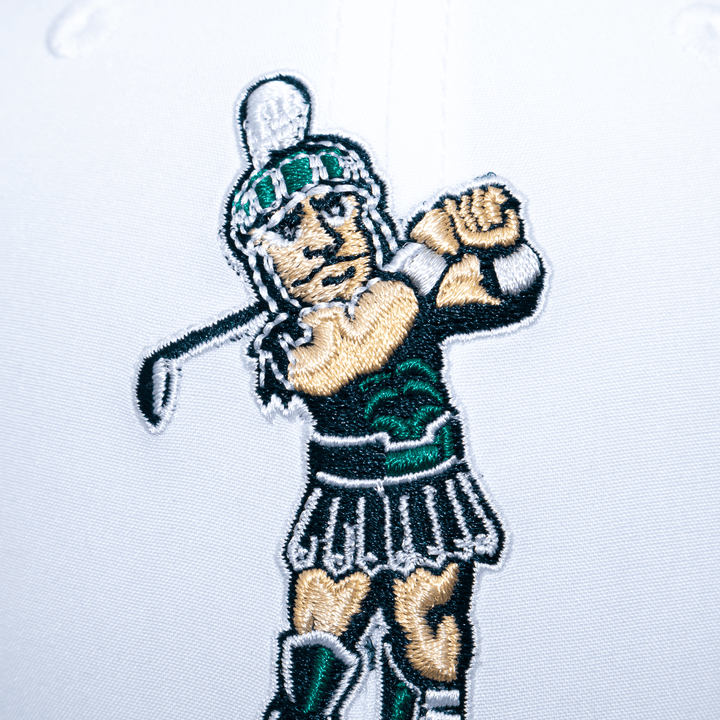 Close up view of the golfing Sparty logo embroidered on a white Michigan State hat.