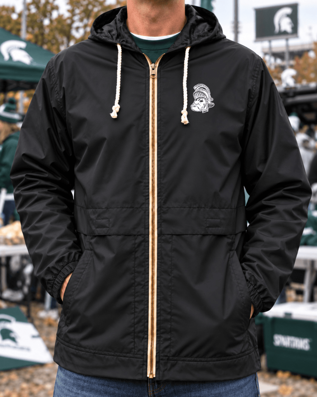 Image of male model wearing black Michigan State raincoat with hood outside Spartan Stadium.