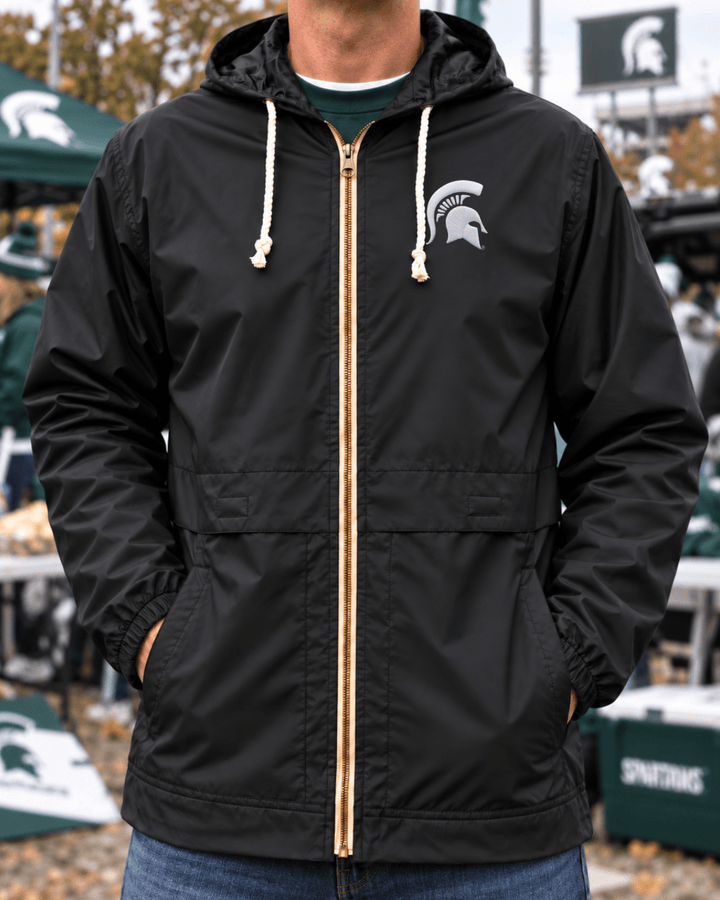 Image of male model wearing black Michigan State raincoat with hood outside Spartan Stadium.