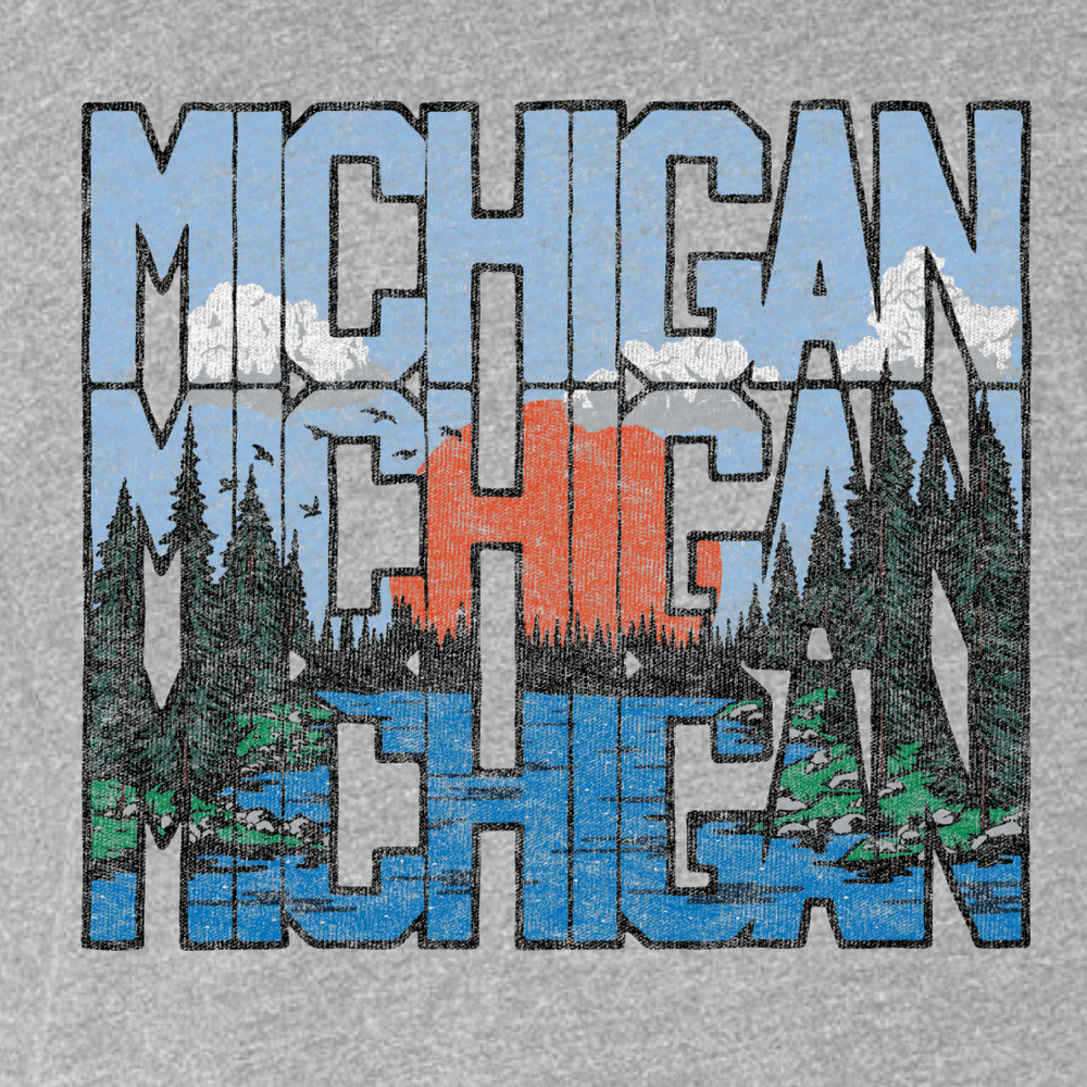 Close-up of a heather grey t-shirt with a bold “MICHIGAN” graphic repeated three times, filled with a scenic nature design including trees, a river, and a sunset, screen printed for a vintage outdoor look