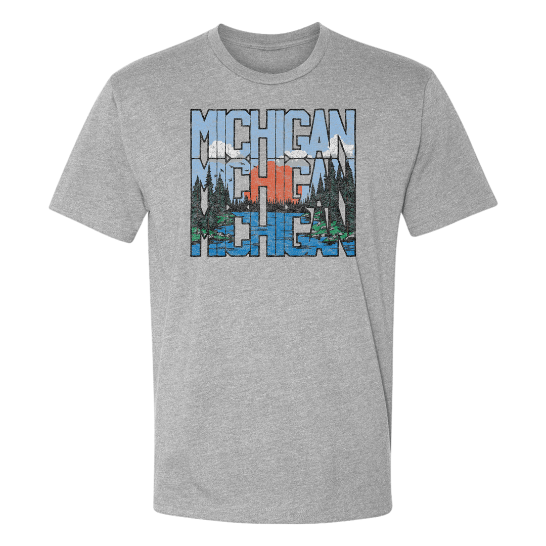 Heather grey unisex t-shirt displayed on a white background, featuring a stacked “MICHIGAN” design with a forest, lake, and sunset scene embedded in the text - perfect for outdoor and lake life enthusiasts