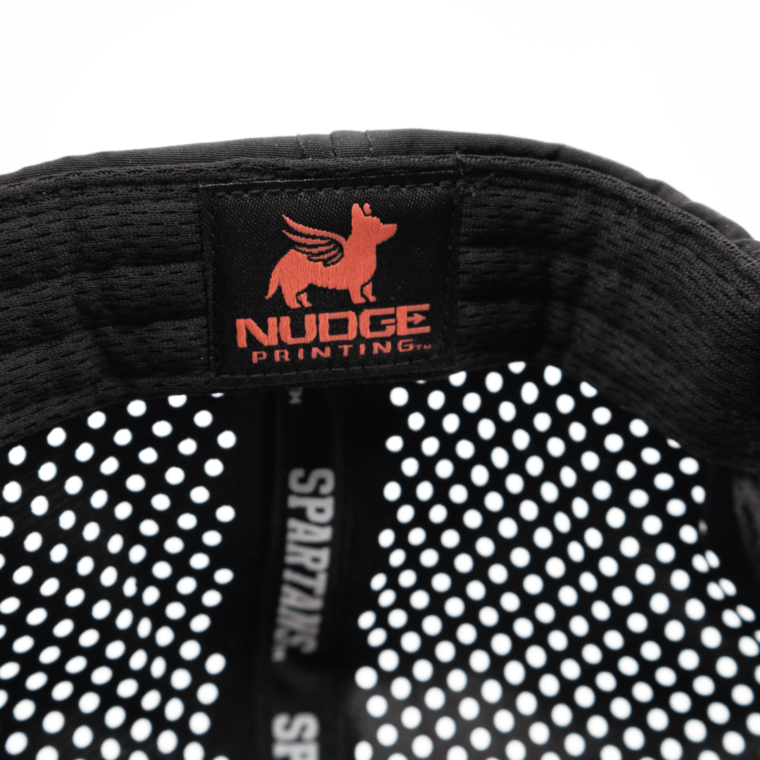 Close up of a black Nudge Printing hat showing the logo labeled inside.