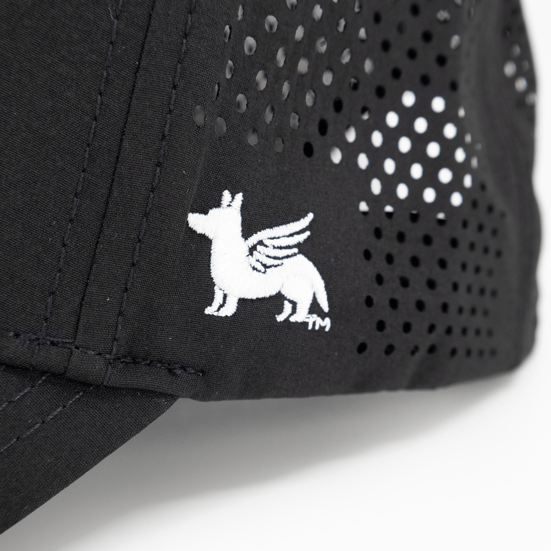 Close up view of a Nudge Printing black hat showing the logo in white thread.