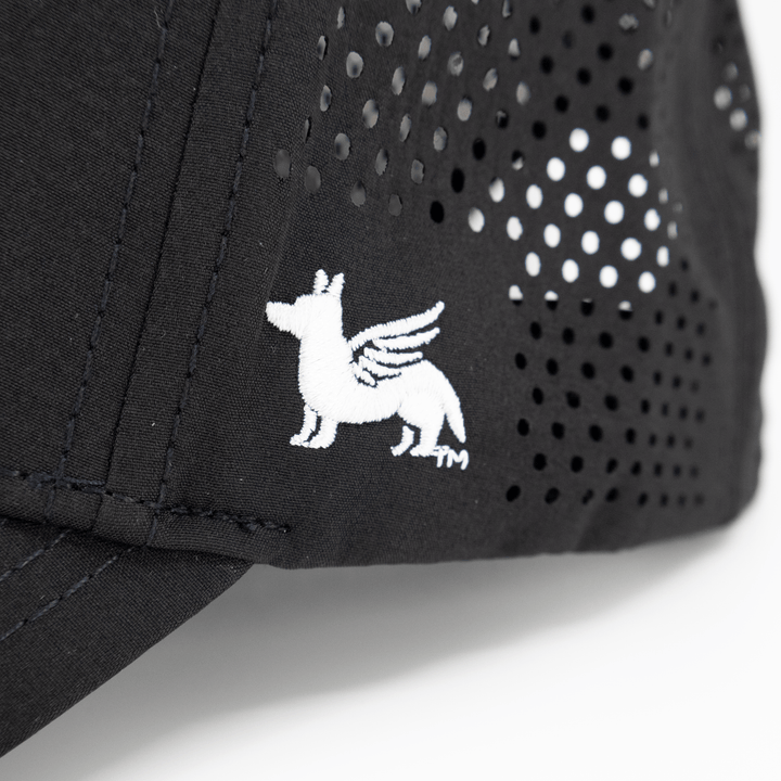 Close up view of a Nudge Printing black hat showing the logo in white thread.