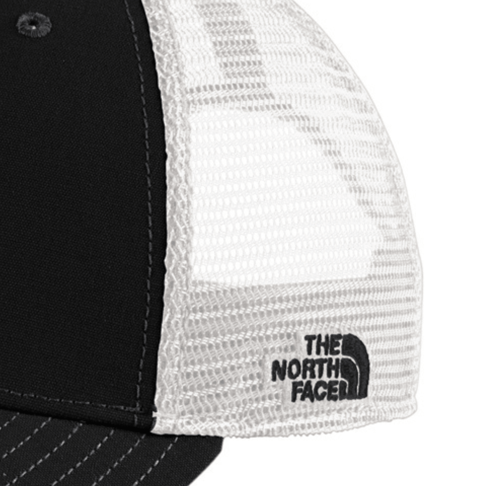 Close-up of the side mesh panel on the black The North Face Michigan State trucker hat showing the embroidered The North Face logo on the white mesh.