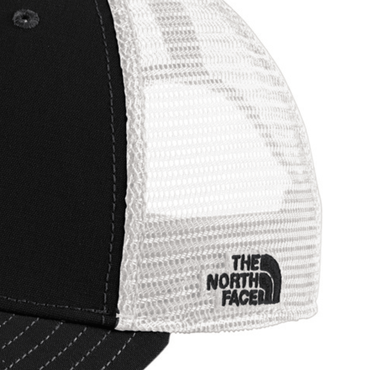 Close-up of the side mesh panel on the black The North Face Michigan State trucker hat showing the embroidered The North Face logo on the white mesh.