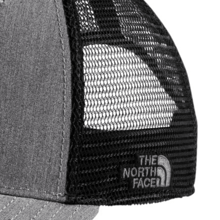 Close-up of the side mesh panel on the heather grey The North Face Michigan State trucker hat showing the embroidered The North Face logo.