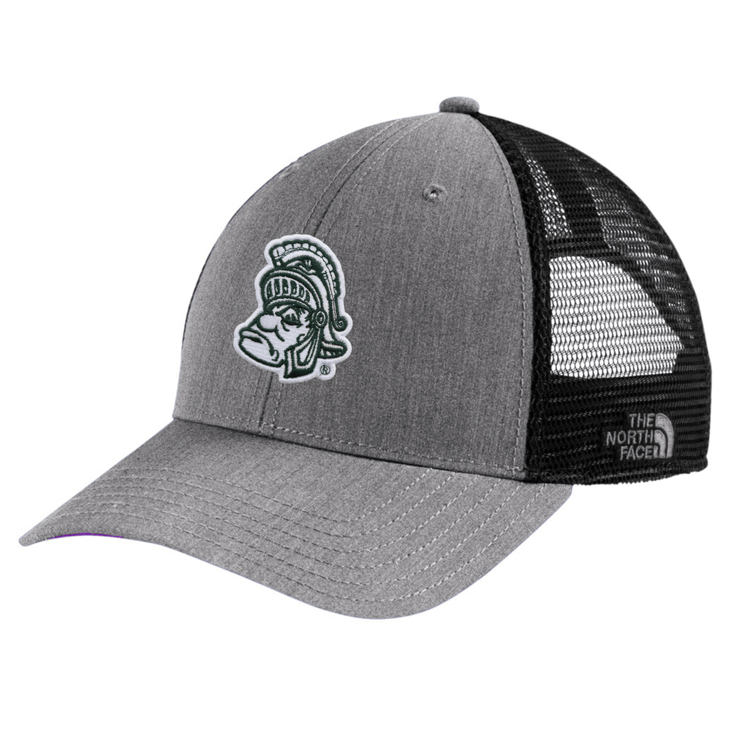 Angled view of heather grey The North Face Michigan State trucker hat with embroidered Gruff Sparty patch on the front and black mesh back panels with The North Face brand label.