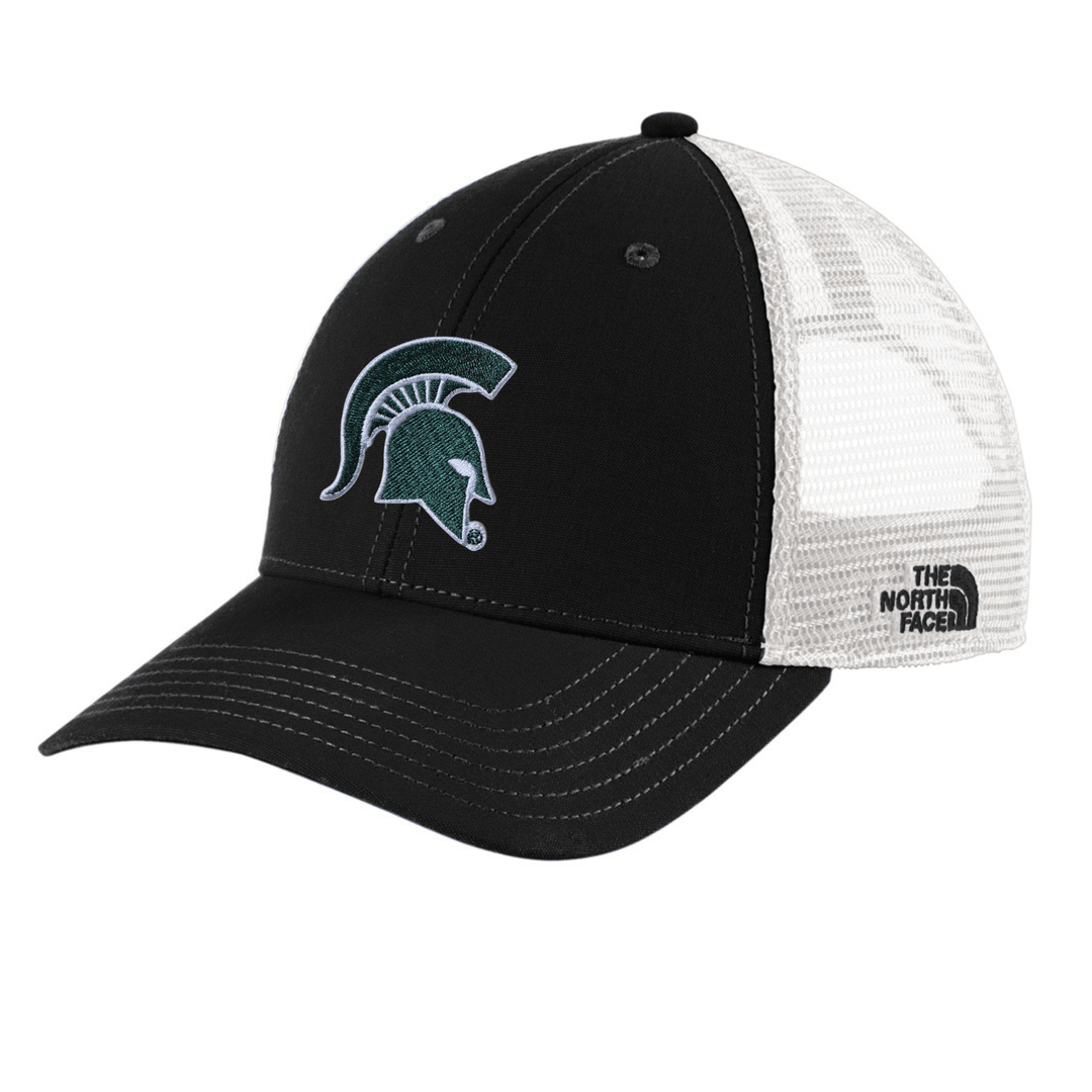 Angled view of black The North Face Michigan State trucker hat with embroidered green Spartan helmet logo on the front and white mesh back panels with The North Face brand label.