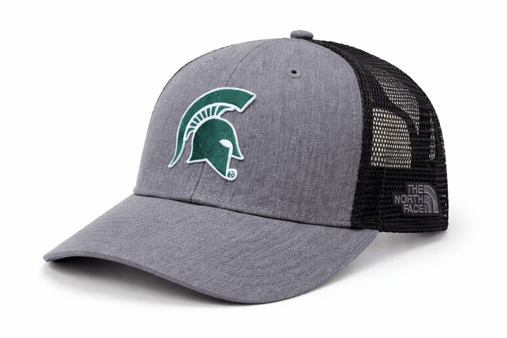 Angled view of heather grey The North Face Michigan State trucker hat with embroidered green Spartan helmet logo on the front and black mesh back panels with The North Face brand label.