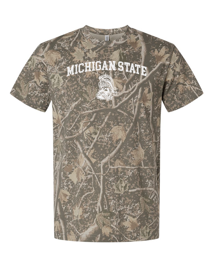 A short-sleeve crewneck t-shirt featuring a full-bleed Realtree Edge camouflage pattern in shades of brown, beige, and gray. The front has a white graphic print reading &