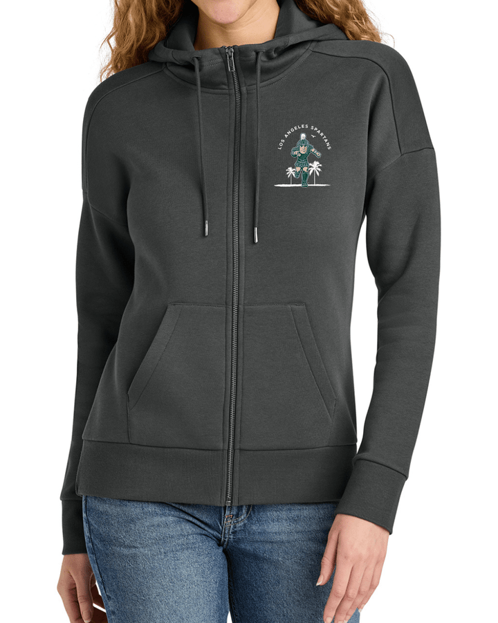 In person shot of woman wearing grey zip up Michigan State Los Angeles Spartans sweatshirt. 
