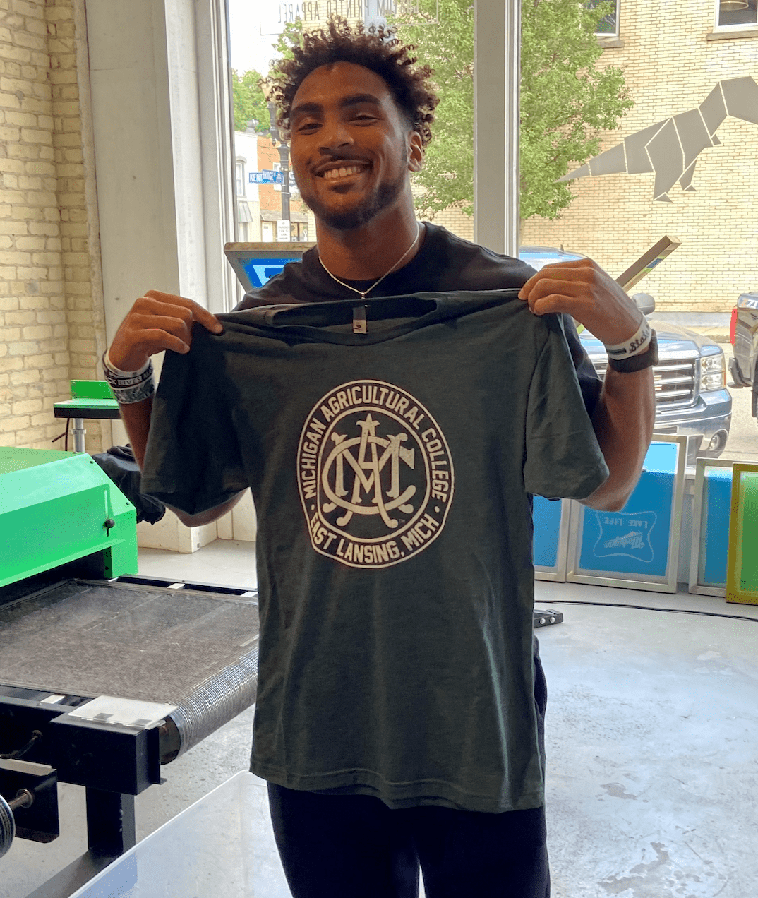 Vintage Green Michigan State MAC T Shirt being held by MSU Football Player Dillon Tatum